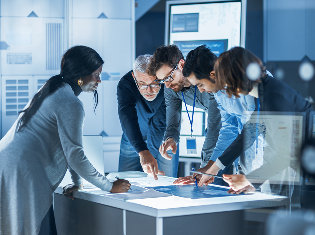 Team of professionals collaborating around a lit table in a modern office environment, symbolizing dynamic career opportunities in innovation, technology, and engineering.
