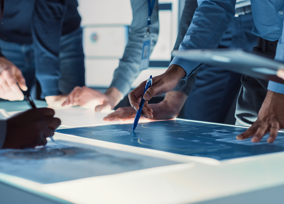 Professionals collaborate on technical plans at a modern workspace, highlighting precision services and teamwork for project development and execution.