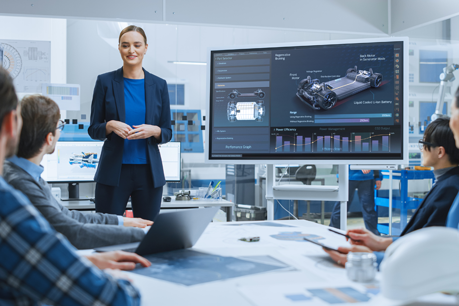 An engineer presenting advanced automotive concepts and performance data on a screen during a collaborative team meeting, symbolizing innovation and professional engineering services.