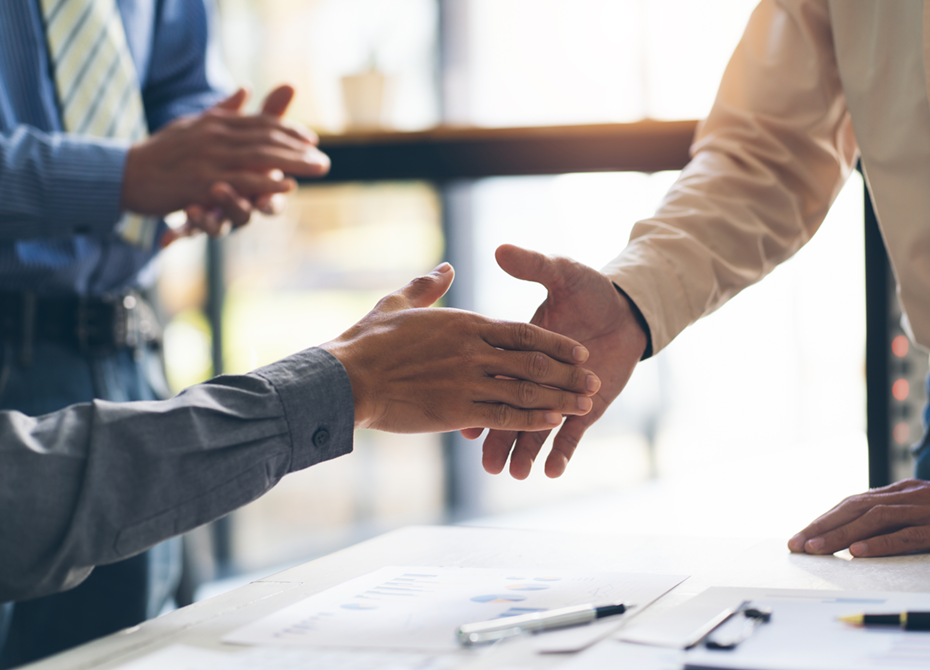 A close-up of two individuals shaking hands in a professional setting, symbolizing trust and accountability. This reflects RLE's social responsibility and commitment to transparency, supported by an effective whistleblower system to ensure ethical business practices.