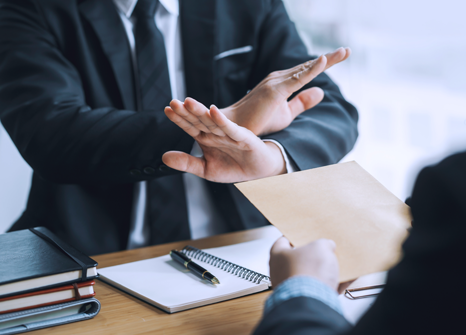 Business professional rejecting an envelope in a gesture symbolizing ethical decision-making and adherence to compliance standards in corporate governance.