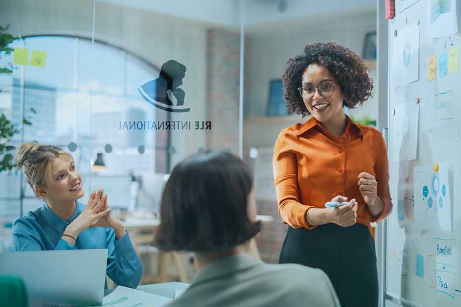 A professional team at RLE International discusses consulting strategies during a collaborative meeting in a modern office space with a whiteboard.