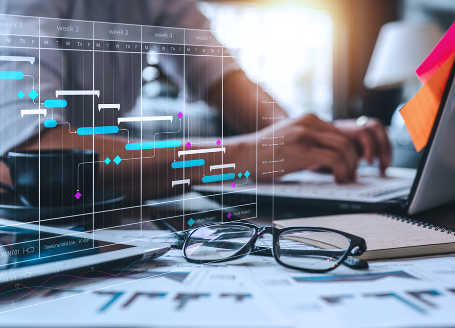 A close-up of a workspace featuring a digital Gantt chart overlay with timelines and tasks, symbolizing effective planning and project business management. The image includes a laptop, documents, glasses, and hands typing, highlighting organized project workflows.