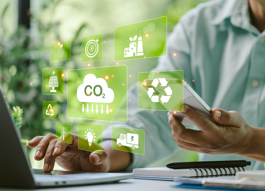 A sustainability consultant works on a laptop and smartphone, analyzing eco-friendly solutions with icons for CO₂ reduction, recycling, renewable energy, and sustainable practices displayed on a digital interface.