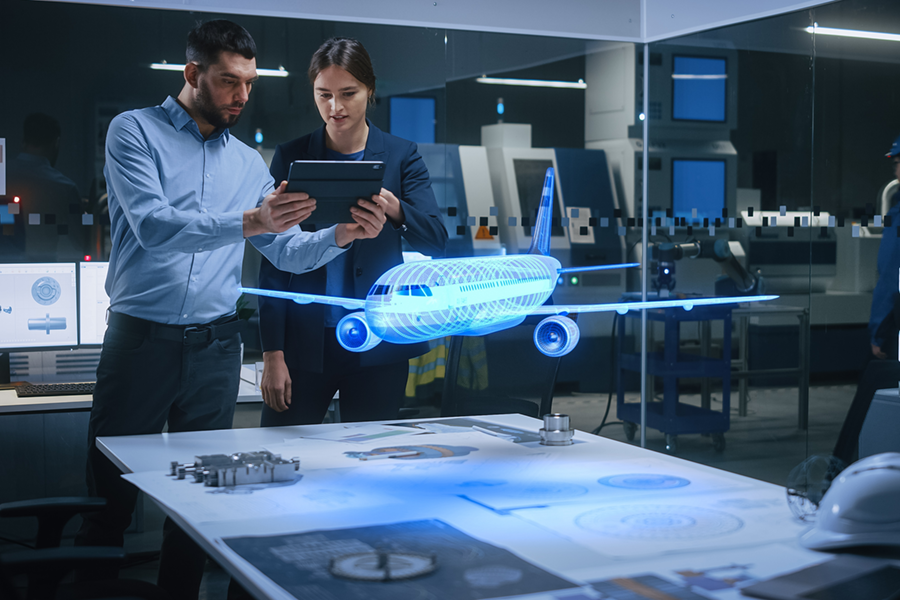 Two engineers in an aviation design office standing next to a table with technical documents and a 3D hologram of an airplane.