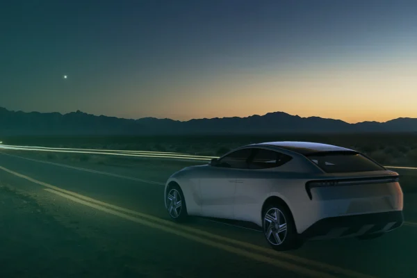 A modern electric vehicle drives along a winding road at dusk, combining advanced innovation in mobility solutions developed by RLE International.